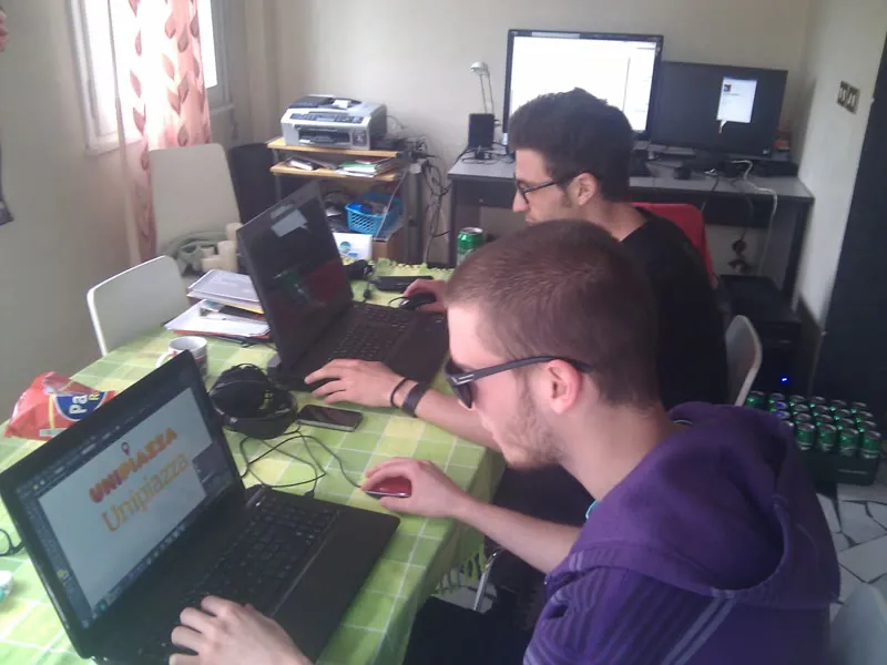 I primi progetti di Unipiazza nel 2013, al lavoro su un tavolo di casa con il primo logo arancione sullo schermo