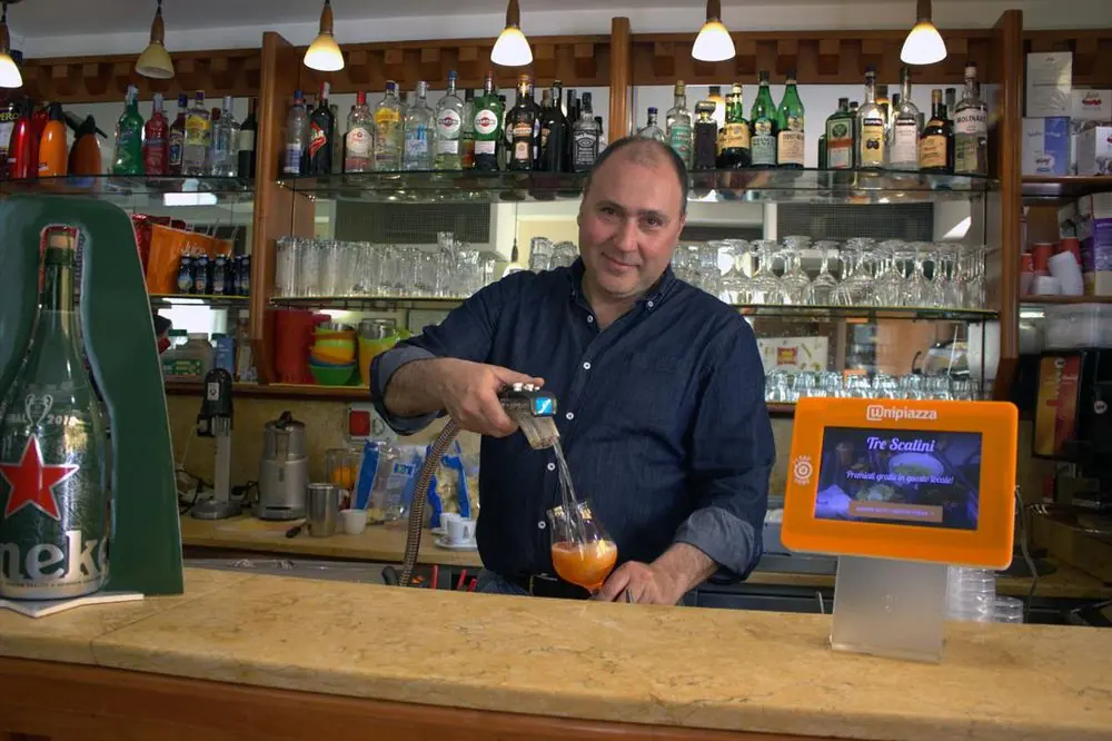Alessandro Chiarotto al bancone del Bar Tre Scalini, con il Chiosco Unipiazza