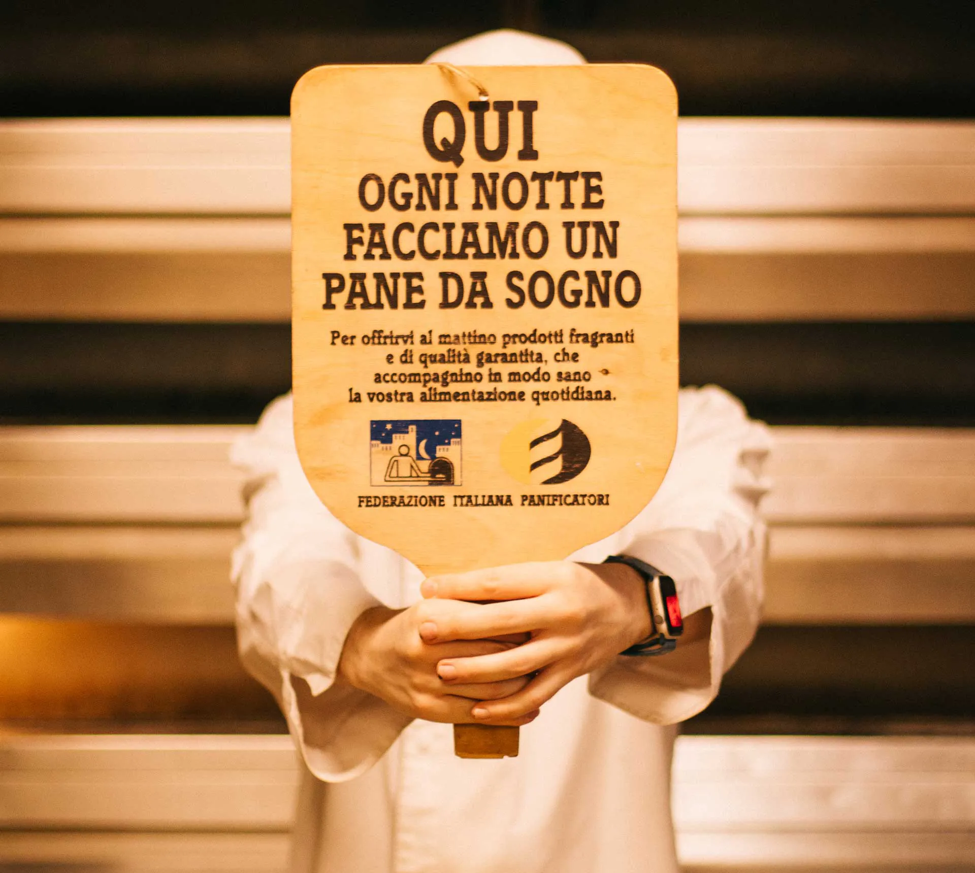 Un panettiere regge il cartello «Qui ogni notte facciamo un pane da sogno»